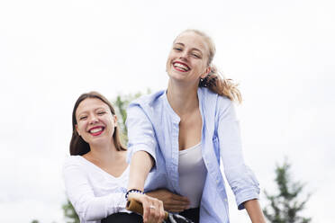 Happy female friends on bicycle - SGF02840