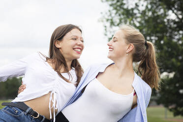 Happy female friends looking at each other while enjoying in nature - SGF02845