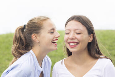 Happy female friends with eyes closed gossiping in nature - SGF02848