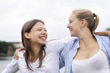 Young women with arm around looking at each other - SGF02851