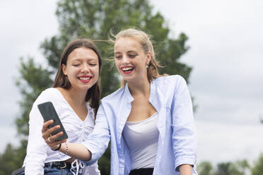 Junge Frau nimmt Selfie durch Handy mit weiblichen Freund - SGF02859
