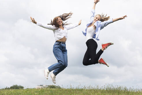 Fröhliche junge Frauen springen auf Gras - SGF02863