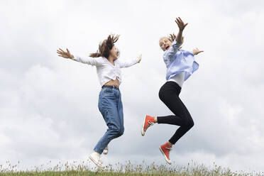 Unbekümmerte junge Freundinnen springen auf Gras - SGF02864
