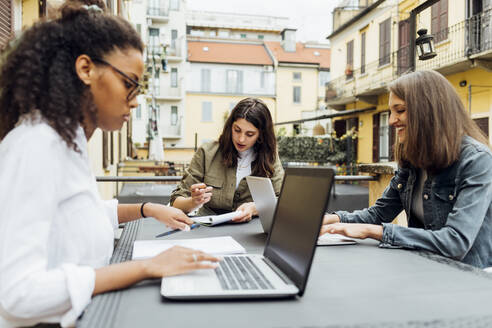 Geschäftsfrauen mit Laptop auf der Terrasse sitzend - MEUF03465