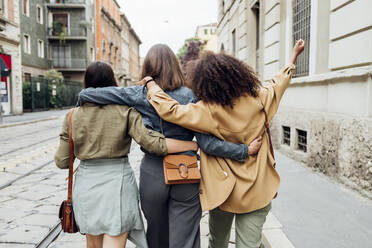 Friends walking with arm around at city street - MEUF03486