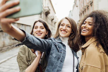 Fröhliche Freunde machen ein Selfie mit ihrem Mobiltelefon - MEUF03492