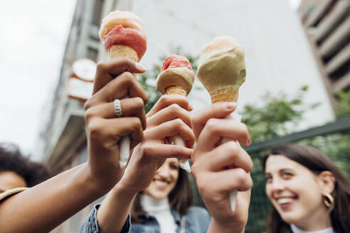 Women holding ice creams together - MEUF03509