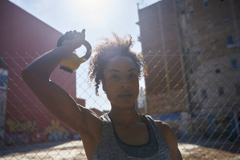 Sportlerin mit Kettlebell beim Training an einem sonnigen Tag - PACF00214