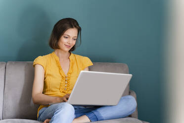 Mittlere erwachsene Frau, die bei der Arbeit zu Hause einen Laptop benutzt - DIGF16106