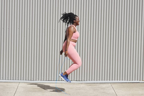 Plus size woman skipping over footpath on sunny day - AODF00551