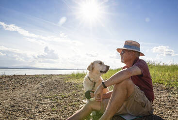 Älterer Mann mit Hund am Trasimeno-See an einem sonnigen Tag - MAMF01933