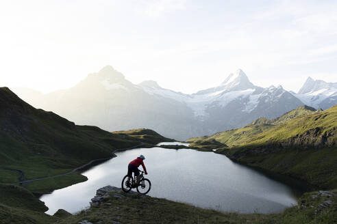 Mountain biker riding downhill at Bachalpsee lake at dawn, Grindelwald, Bernese Oberland, Bern Canton, Switzerland, Europe - RHPLF19996