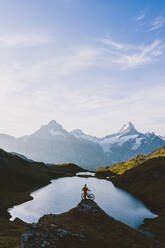 Mountain biker looking at Bachalpsee lake and Bernese Oberland mountains at dawn, Grindelwald, Bern Canton, Switzerland, Europe - RHPLF20000