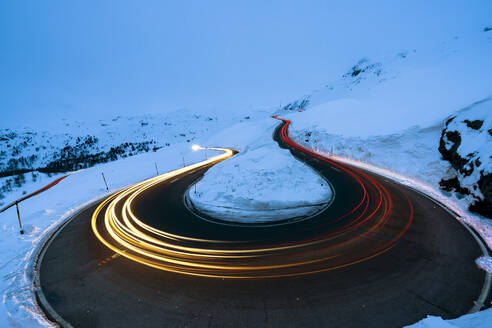 Autoscheinwerfer in den Kurven der Berninapassstrasse im Winter, Val Poschiavo, Kanton Graubünden, Engadin, Schweiz, Europa - RHPLF20099