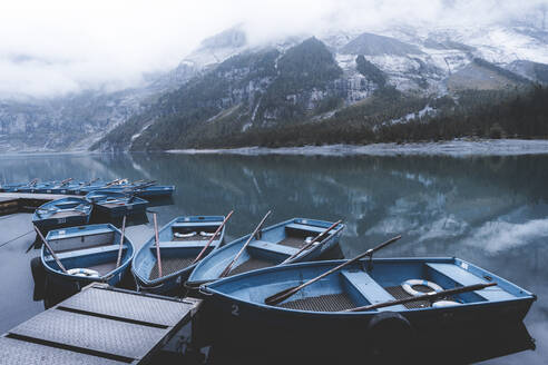 Row boats moored on shore of lake Oeschinensee on a foggy day, Bernese Oberland, Kandersteg, Bern canton, Switzerland, Eurpe - RHPLF20109