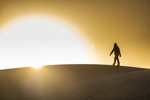 Mann geht im Gegenlicht auf einer Sanddüne, Tenere-Wüste, Niger, Westafrika, Afrika - RHPLF20179