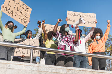 From below of crowd of multiracial protesters with placards and megaphone standing on street during Black Lives Matter protest - ADSF26080