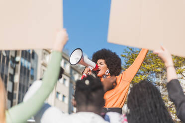 Afroamerikanische Kämpferin für soziale Gerechtigkeit mit Rednerin gegen Ernte anonyme, multirassische Menschen mit Plakaten, die in der Stadt für Menschenrechte kämpfen - ADSF26082