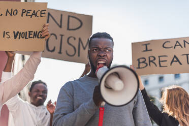Ein männlicher Afroamerikaner schreit in ein Megaphon während eines Black Lives Matter-Protests in der Stadt, während er in einer Menge von multiethnischen Demonstranten steht - ADSF26085