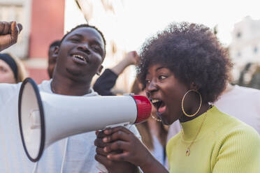 Seitenansicht eines Afroamerikaners in weiblicher Gestalt, der in ein Megaphon schreit, während er gegen Rassendiskriminierung während der Black Lives Matter Demonstration protestiert - ADSF26092