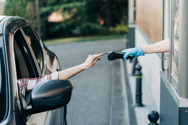 Unbekannte Person, die mit einer Plastikkarte am POS-Terminal in einem Drive-In-Fastfood-Café bezahlt - ADSF26119