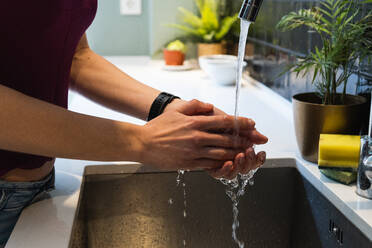 Crop unerkennbar weiblichen Waschen der Hände unter reinen Wasserfluss aus dem Wasserhahn in Haus Küche - ADSF26290