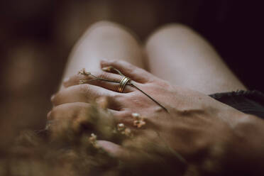 High angle of crop anonymous boyfriend with ring and stem of flower on finger placing hand on girlfriend - ADSF26449