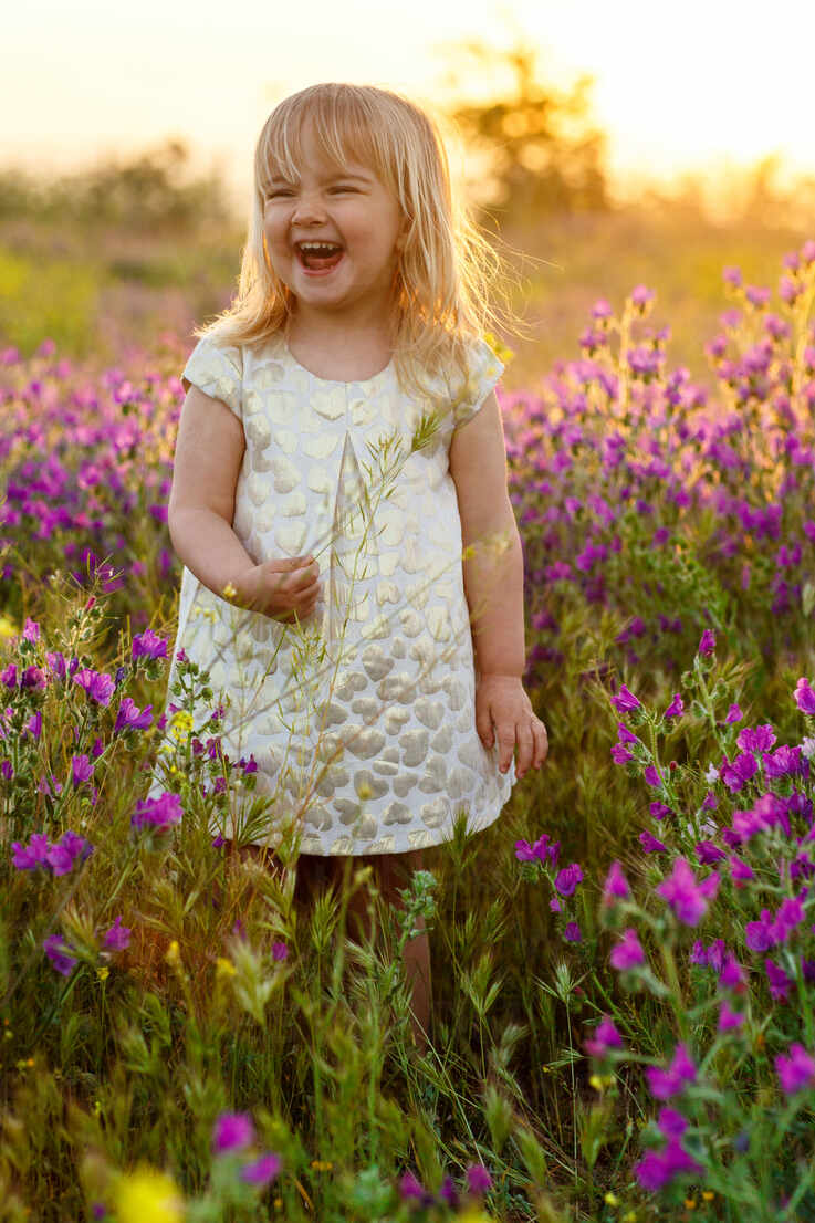 Adorable little girl in white dress laughing and looking away