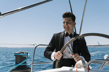 Smiling young man sailing yacht in summer - EGAF02431