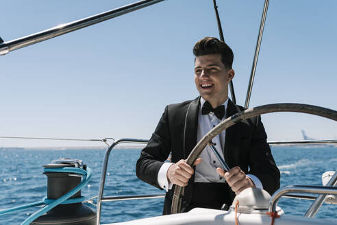 Lächelnder junger Mann beim Segeln auf einer Yacht im Sommer - EGAF02431