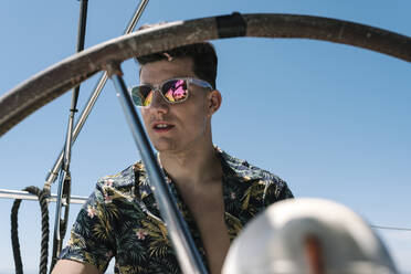 Handsome man seen through helm in yacht during summer - EGAF02439