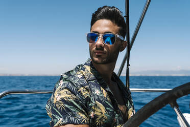 Handsome young man wearing sunglasses traveling in yacht - EGAF02440