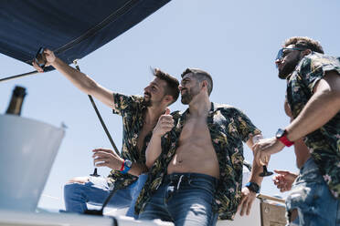 Man taking selfie with male friends in yacht on sunny day - EGAF02450