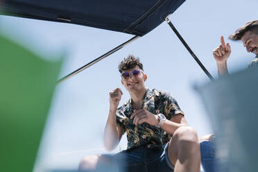 Smiling handsome young man with friend in yacht during vacation - EGAF02455