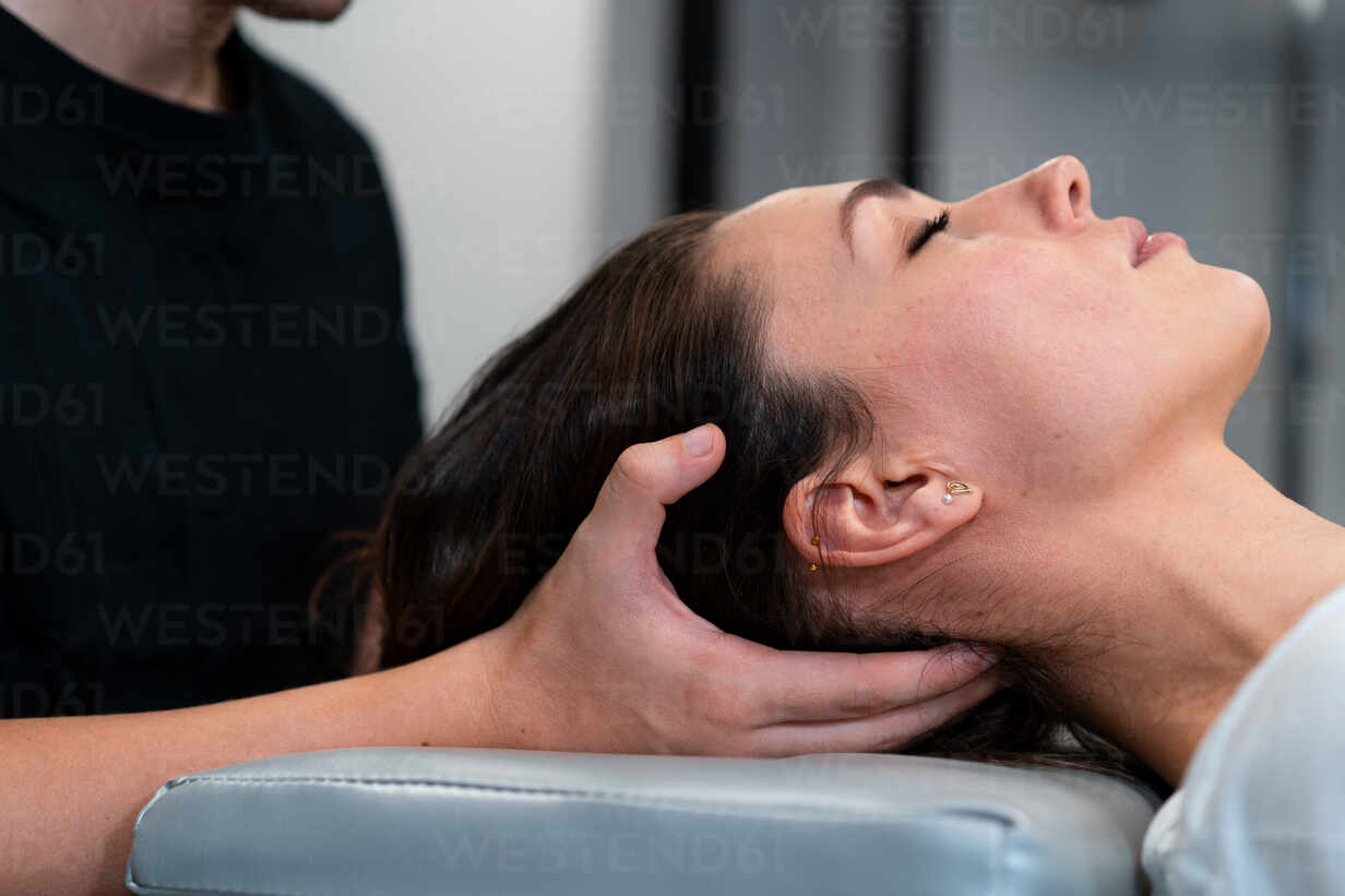Professional male masseur massages neck and shoulders of young woman in  massage parlor., Stock image