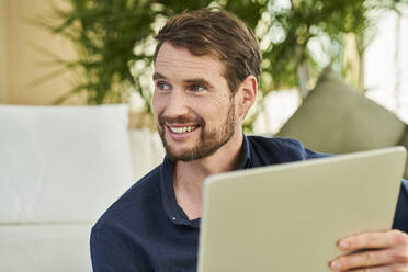 Gut aussehender Geschäftsmann mit braunem Haar, der ein digitales Tablet hält - AKLF00336