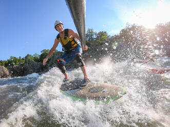 Der Fotograf Skip Brown surft mit dem Stand Up Paddle auf dem anspruchsvollen Wildwasser unterhalb der Great Falls des Potomac River an der Grenze zwischen Virginia und Maryland, Vereinigte Staaten von Amerika, Nordamerika - RHPLF20380