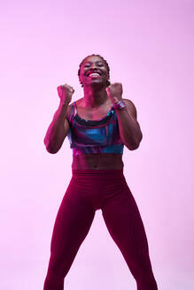 African American sportswoman in activewear demonstrating win gesture while looking at camera with toothy smile - ADSF26641