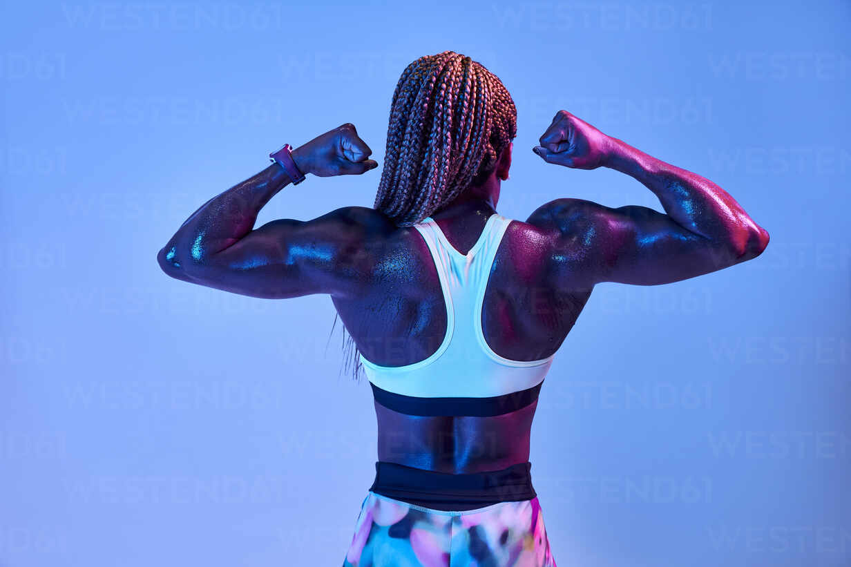 Fotografia do Stock: Sport and women. Rear view of strong fitness athlete,  female bodybuilder, flexing muscles, showing fit body, biceps and athletic  back, smiling satisfied, white background