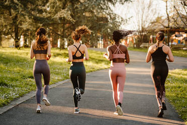 Smiling multiracial female runners in activewear jogging and