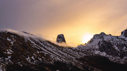 Wide angle landscape of Peaks of Europe range with snow and fog under clouds during sundown - ADSF26779