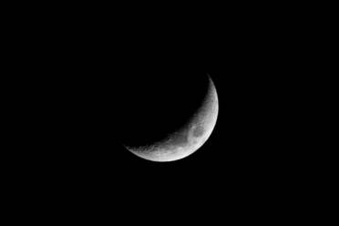 Earth satellite crescent moon with craters illuminated on black dark sky at night - ADSF26790