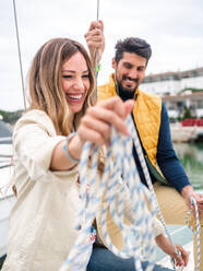 Content woman with ethnic boyfriend spending time on yacht in city port in daylight - ADSF26877