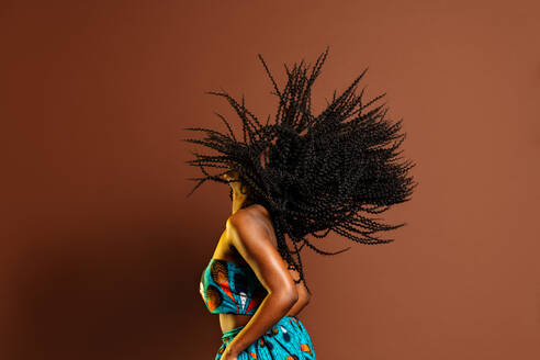 Seitenansicht einer nicht erkennbaren afroamerikanischen Frau, die sich beim Tanzen im Studio die Haare dreht - ADSF26937