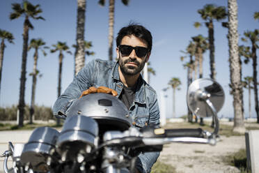 Handsome young man with helmet sitting on motorcycle during sunny day - RCPF01202