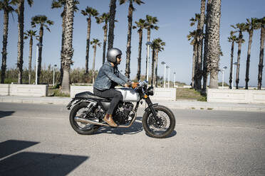 Young man riding motorcycle on sunny day - RCPF01207