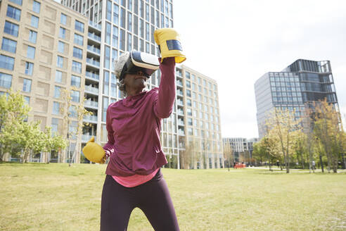 Aktive Frau beim Boxen mit Virtual-Reality-Headset im Park - PMF01995