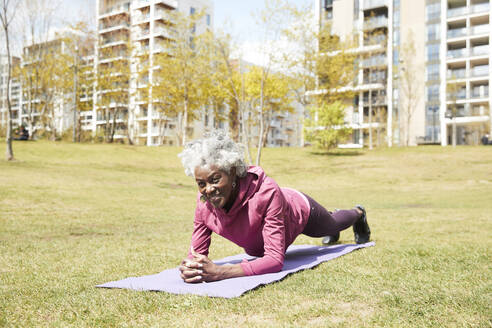 Ältere Frau in Plank-Position auf einer Übungsmatte in einem öffentlichen Park - PMF01998