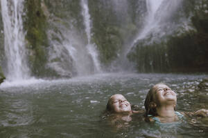 Lächelnde Mädchen mit geschlossenen Augen haben Spaß im Wasser - LJF02213