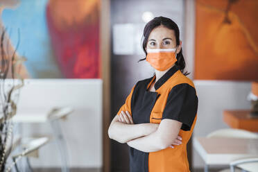 Kellnerin mit Gesichtsschutzmaske in der Cafeteria während der Pandemie - LJF02218